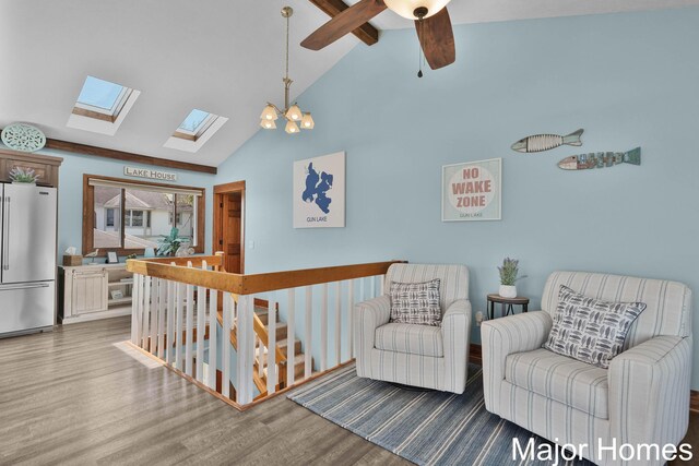 sitting room featuring wood finished floors, a skylight, an upstairs landing, beamed ceiling, and high vaulted ceiling