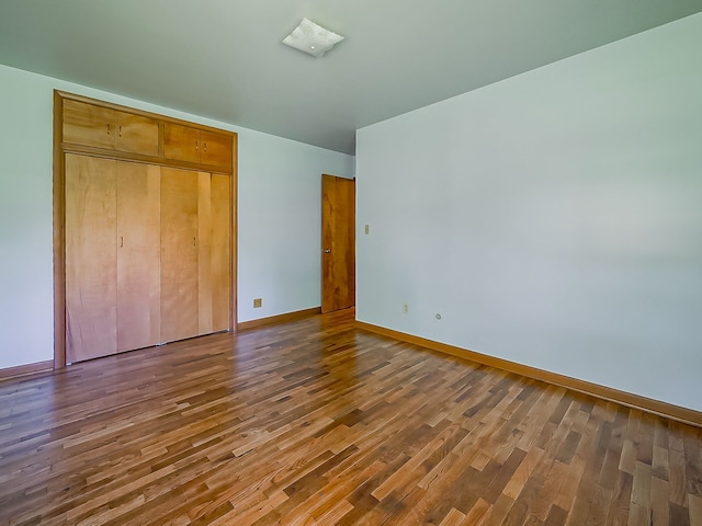 unfurnished bedroom with wood finished floors, baseboards, and a closet