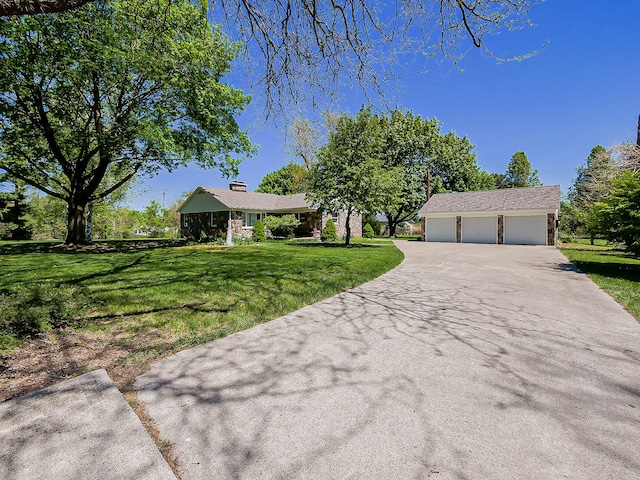 view of front of property featuring an outbuilding, a garage, a front lawn, driveway, and a chimney