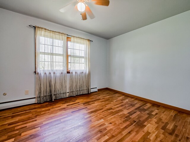 empty room featuring wood finished floors, a ceiling fan, baseboards, and baseboard heating