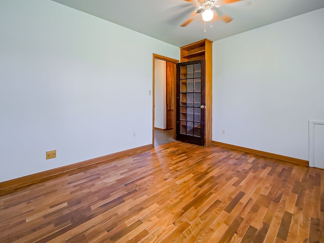 spare room featuring a ceiling fan, wood finished floors, and baseboards