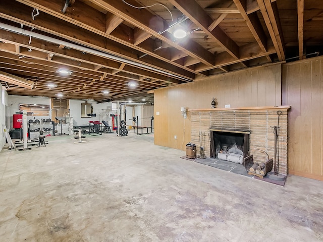 basement featuring a brick fireplace and wood walls