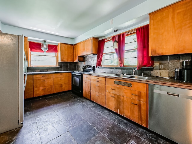 kitchen with appliances with stainless steel finishes, decorative backsplash, a sink, and healthy amount of natural light