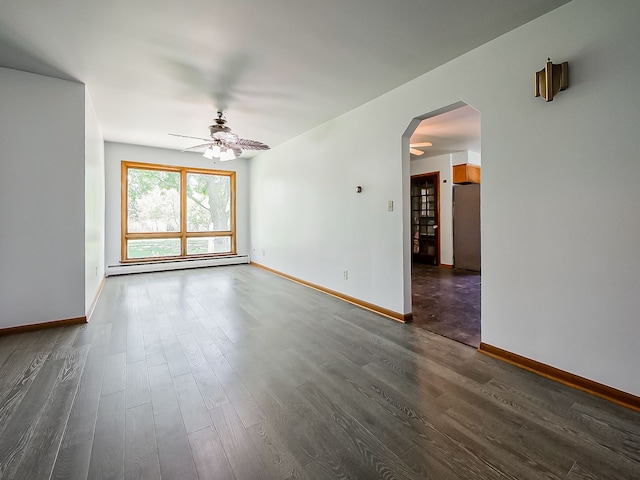 unfurnished room with arched walkways, a baseboard heating unit, a ceiling fan, dark wood-style flooring, and baseboards