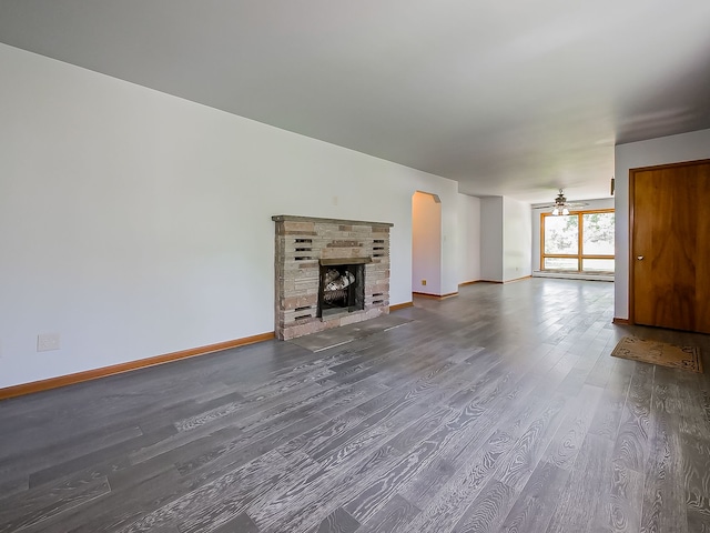 unfurnished living room featuring wood finished floors, baseboards, and a stone fireplace