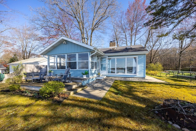 10401 N Chippewa Dr, Evart, MI 49631 - back of property featuring a chimney, a sunroom, a lawn, and a trampoline