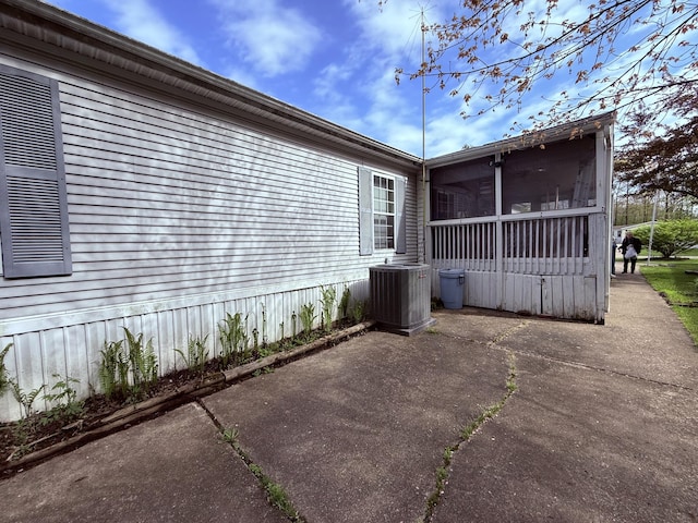 view of side of home with cooling unit, a sunroom, and a patio area