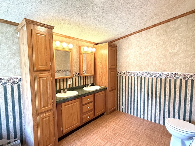 full bath featuring ornamental molding, wallpapered walls, a textured ceiling, double vanity, and toilet