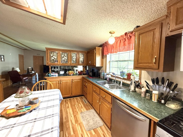 kitchen featuring a sink, dishwasher, a textured ceiling, brown cabinetry, and light wood-style flooring
