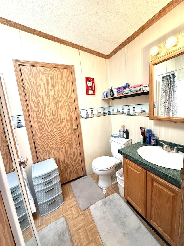 full bath with crown molding, vanity, toilet, a textured ceiling, and wood walls