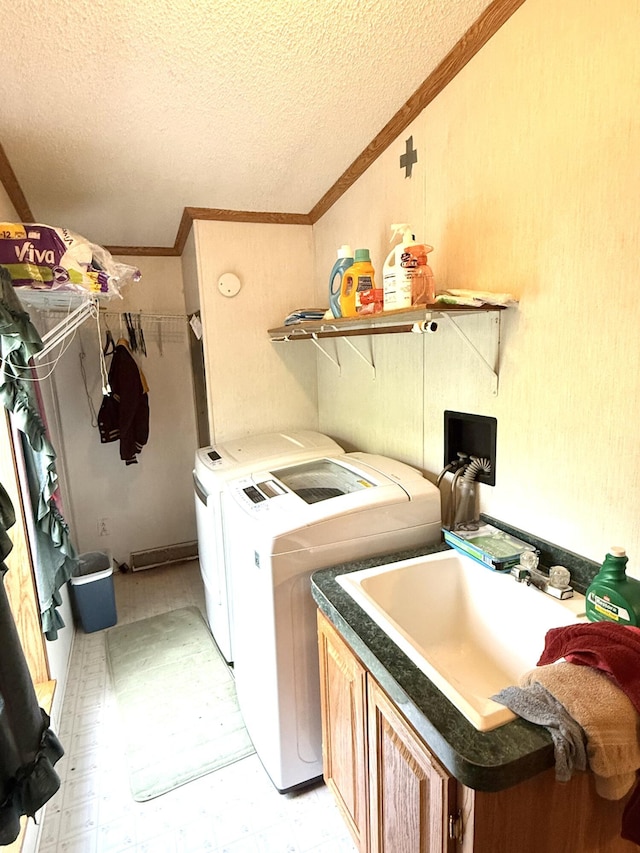 laundry room featuring washing machine and dryer, a textured ceiling, crown molding, cabinet space, and light flooring