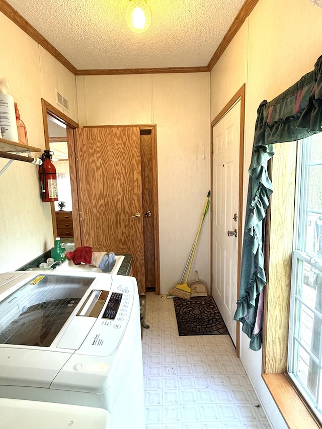 laundry room with independent washer and dryer, ornamental molding, a textured ceiling, and light flooring
