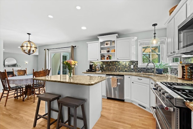 3645 Sandbar Dr, Commerce Twp, MI 48382 - kitchen featuring stainless steel appliances, a sink, decorative backsplash, a center island, and white cabinetry