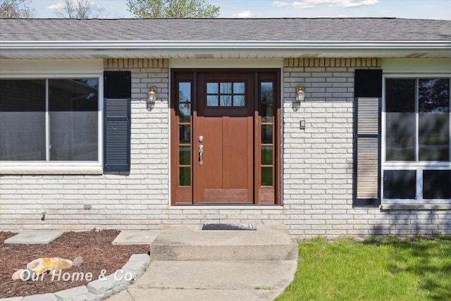 property entrance featuring brick siding and roof with shingles