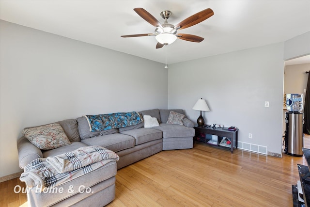 living area featuring ceiling fan, light wood finished floors, and baseboards