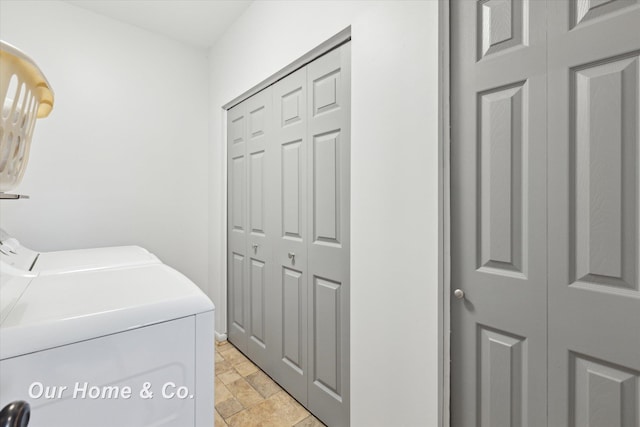 clothes washing area featuring washing machine and dryer and light stone finish floors