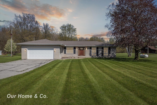 ranch-style house with a garage, a lawn, driveway, and brick siding