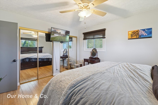 bedroom with a textured ceiling, hardwood / wood-style floors, and a ceiling fan