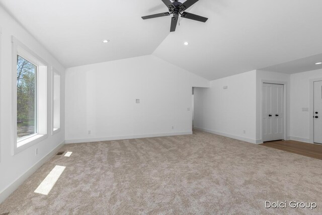 unfurnished living room with carpet floors, plenty of natural light, ceiling fan, lofted ceiling, and baseboards