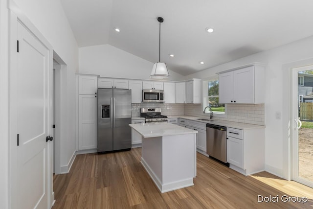 kitchen featuring appliances with stainless steel finishes, wood finished floors, vaulted ceiling, backsplash, and recessed lighting