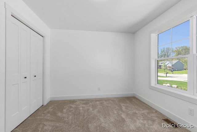 unfurnished bedroom featuring carpet, baseboards, and a closet