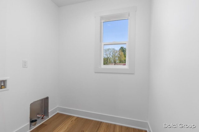 clothes washing area with baseboards, washer hookup, and wood finished floors