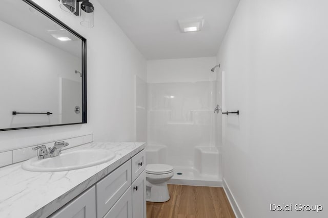 full bathroom featuring a shower, toilet, wood finished floors, vanity, and baseboards