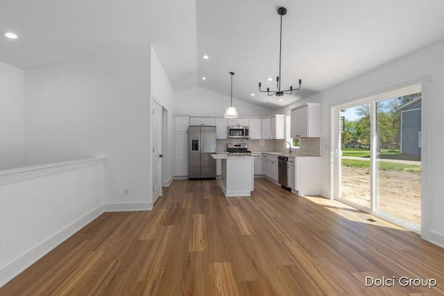 kitchen with appliances with stainless steel finishes, lofted ceiling, light wood-style floors, light countertops, and a chandelier