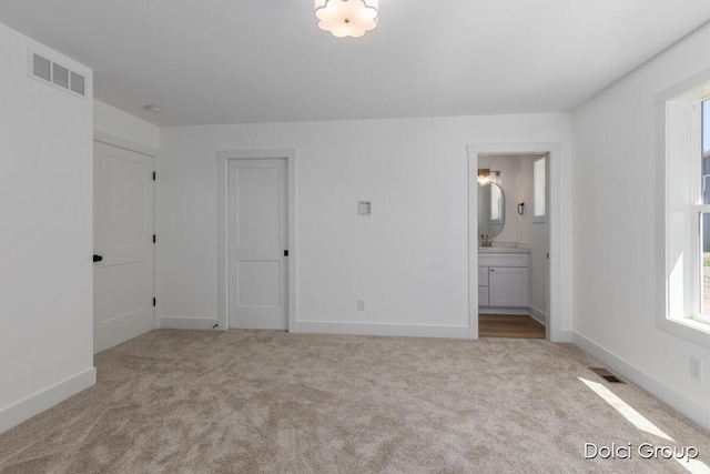unfurnished bedroom featuring carpet, baseboards, and ensuite bathroom