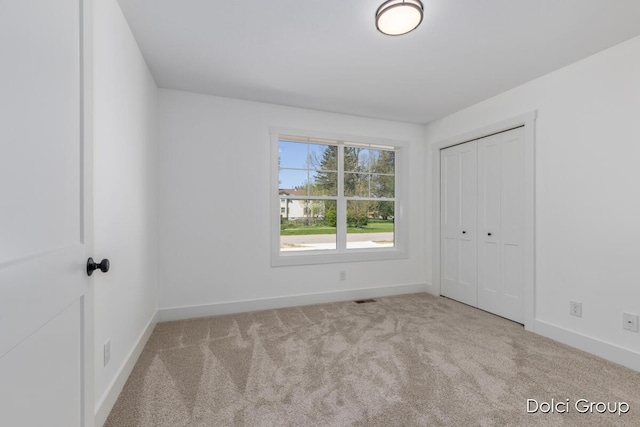 unfurnished bedroom with carpet flooring, baseboards, and a closet