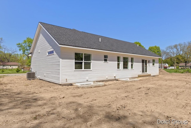 back of property with central AC unit and roof with shingles