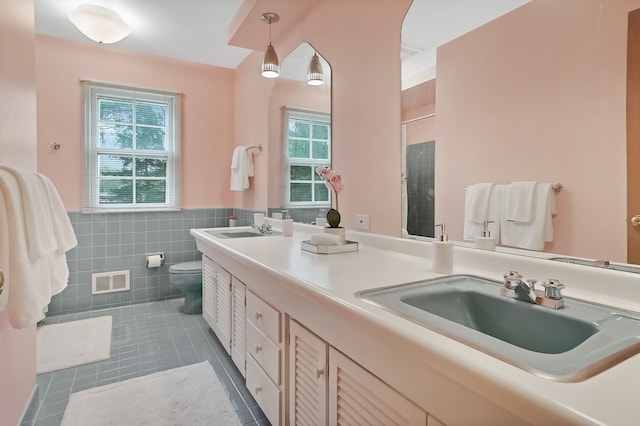 bathroom with tile patterned floors, toilet, a stall shower, tile walls, and a wainscoted wall
