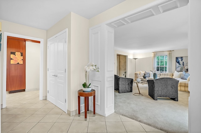 hall featuring light carpet, light tile patterned flooring, and baseboards