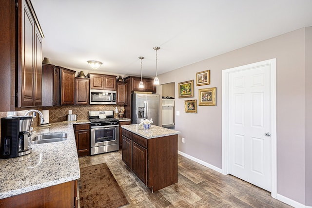 754 Autumn Valley Dr, Ortonville, MI 48462 - kitchen with appliances with stainless steel finishes, a sink, a kitchen island, baseboards, and tasteful backsplash