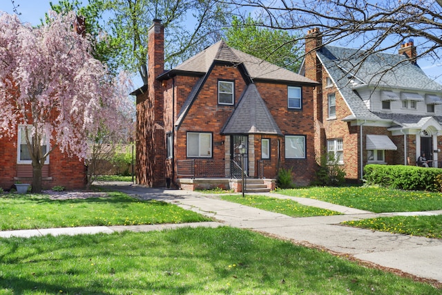 14643 Penrod St, Detroit, MI 48223 - tudor-style house with a chimney, a front yard, brick siding, and a shingled roof