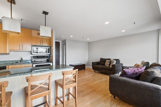 300 Riverfront Dr Unit 300/4C, Detroit, MI 48226 - kitchen featuring stainless steel appliances, a sink, open floor plan, a kitchen bar, and recessed lighting