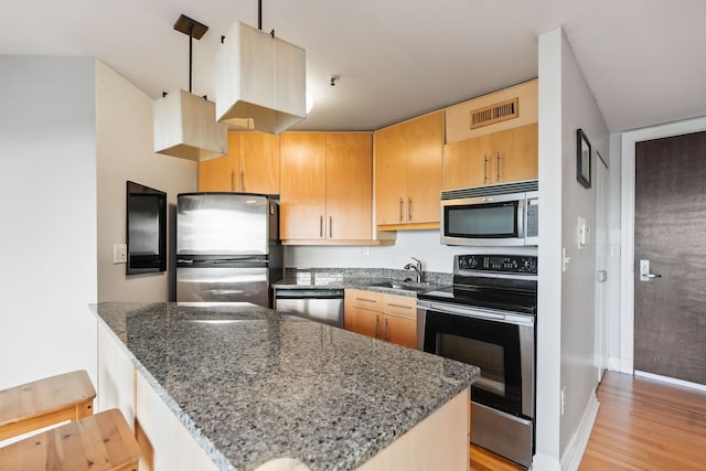 300 Riverfront Dr Unit 300/4C, Detroit, MI 48226 - kitchen featuring appliances with stainless steel finishes, dark stone countertops, a sink, light wood-style floors, and baseboards