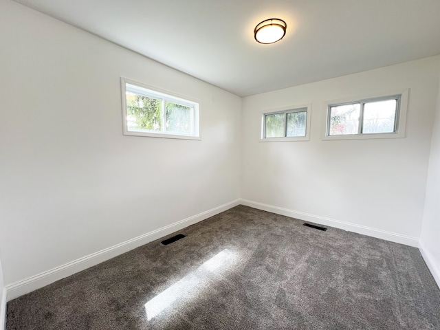 empty room with dark carpet and baseboards
