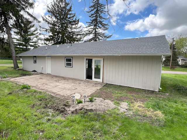 rear view of property with a patio area, a lawn, and roof with shingles