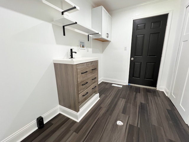 washroom with washer hookup, baseboards, dark wood-style floors, crown molding, and cabinet space
