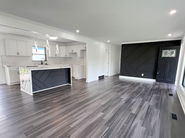 unfurnished living room with crown molding, baseboards, dark wood-style flooring, a sink, and recessed lighting