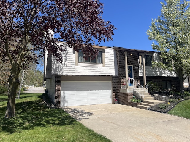 bi-level home with an attached garage, driveway, brick siding, and a front lawn
