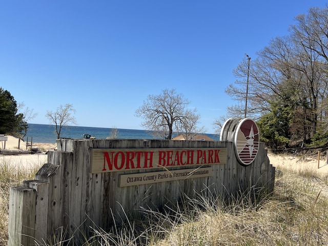 community / neighborhood sign featuring view of water and beach