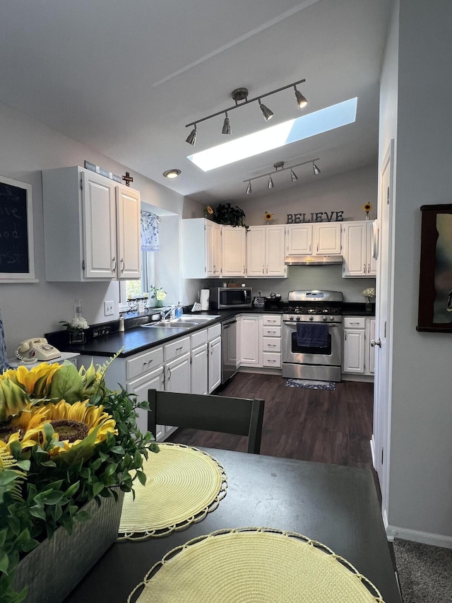 kitchen with appliances with stainless steel finishes, a skylight, and white cabinetry