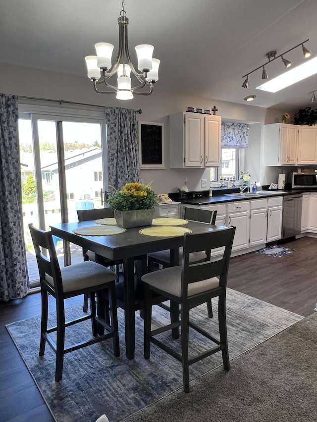 dining space with a chandelier, rail lighting, and dark wood finished floors