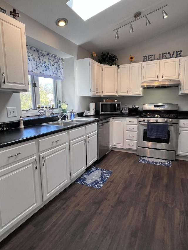 kitchen featuring appliances with stainless steel finishes, under cabinet range hood, dark countertops, white cabinetry, and recessed lighting