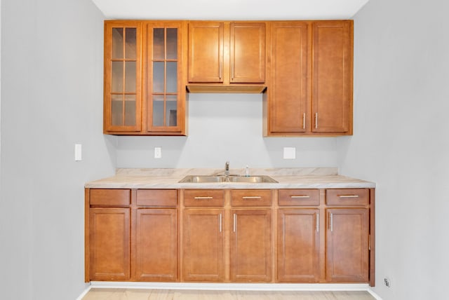 18250 Weaver St, Detroit, MI 48228 - kitchen featuring a sink, light countertops, glass insert cabinets, and brown cabinetry