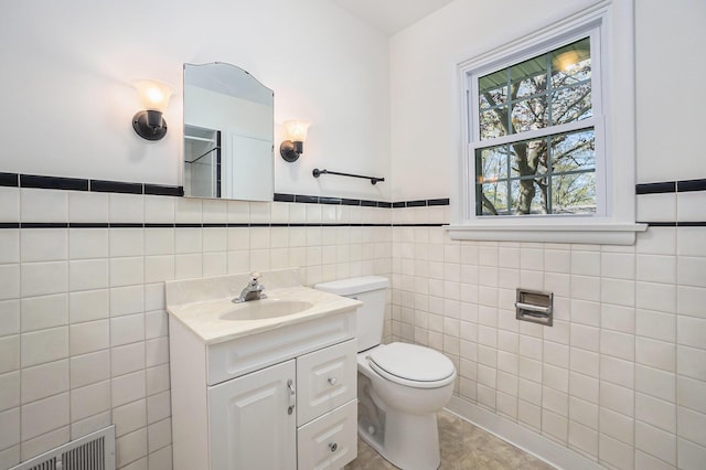 615 Garber Rd, North Muskegon, MI 49445 - full bathroom with tile walls, toilet, vanity, and a wainscoted wall