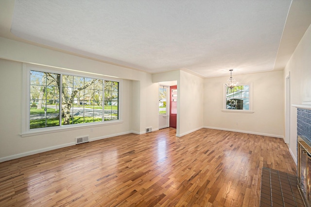 615 Garber Rd, North Muskegon, MI 49445 - unfurnished living room with a chandelier, light wood-style floors, a fireplace, and baseboards