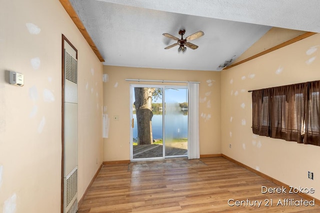 771 Sunny Trl, Greenville, MI 48838 - empty room with ceiling fan, wood finished floors, baseboards, vaulted ceiling, and a water view